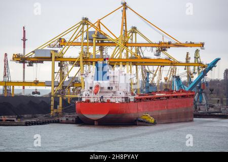 Terminal portuale di carbone con navi sotto scarico. Terminal di carbone del porto marittimo. Cumuli di carbone in porto in attesa di carico su nave e spedizione tutti o Foto Stock