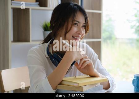Ritratto di donna asiatica allegra con vita casual sulla scrivania in ufficio a casa. Concetto di giovani uomini d'affari che lavorano a casa Foto Stock