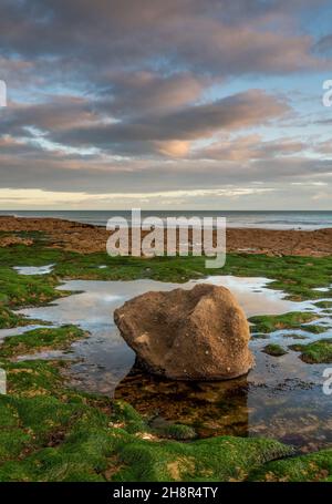 Solitaria pietra solitaria sulla spiaggia sull'isola di wight costa in atmosfera di luce moody, linea costiera dell'Isola di Wight, spiaggia con singola grande roccia. Foto Stock