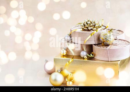 Scatole regalo kraft per Natale o Capodanno, palline per le vacanze d'oro su uno sfondo bokeh di luci scintillanti di ghirlanda, spazio copia Foto Stock