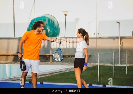 Due giocatori di padel si salutano a vicenda facendo il pugno - gli amici di Padel salutano al momento del covid Foto Stock