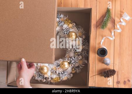 L'artigiano femminile sta imballando una corona di Natale in una scatola da trasmettere al cliente Foto Stock