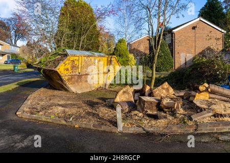 Un grande arrugginito, rifiuti di rifiuti martoriati saltare pieno di rami e rifiuti di giardino sul giardino di fronte di una strada a Surrey, nel sud-est dell'Inghilterra Foto Stock