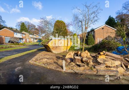 Un grande arrugginito, rifiuti di rifiuti martoriati saltare pieno di rami e rifiuti di giardino sul giardino di fronte di una strada a Surrey, nel sud-est dell'Inghilterra Foto Stock