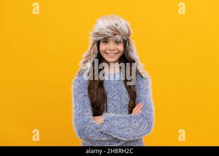 bambino positivo in maglione e cappello con archetto su sfondo giallo, moda stagione Foto Stock