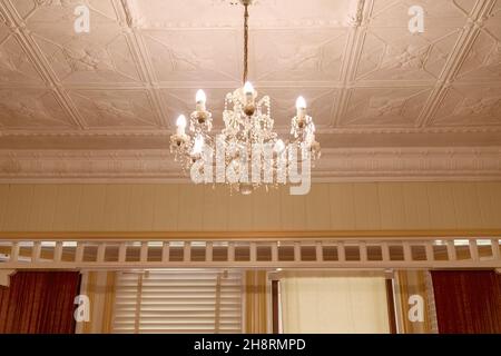 Un lampadario di cristallo appeso a un elegante soffitto in gesso nella storica casa pionieristica della famiglia - miglioramento del grano per replicare l'era della fotografia Foto Stock