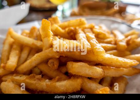 Vista ravvicinata delle patatine fritte e martellate in un cestino rivestito di carta bianca al tavolo del ristorante Foto Stock