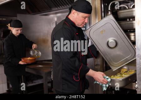 Chef preparandosi piatto fuori dal forno Foto Stock