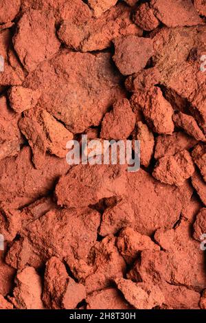 estratto di terra di argilla rossa, ossido di rame contenuto roccia in tonalità rosso profondo, sfondo closeup, struttura, preso dall'alto Foto Stock