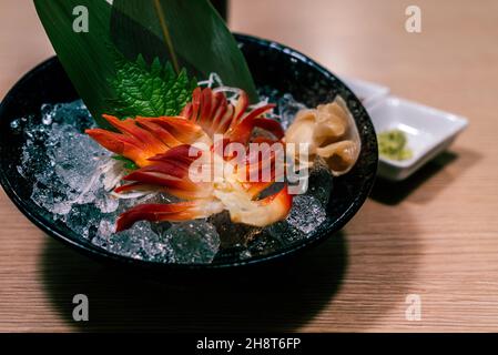 Giapponese Stimpson surf clam o clam pignone o hokkigai sashimi con ghiaccio e vetro nero ciotola sul tavolo. Pesce fresco e crudo con menu sano Giapponese. Foto Stock