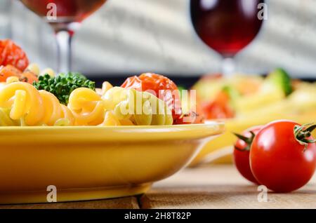 Pasta fusilli con insalata di broccoli, carota, mais, pomodori secchi sul tavolo della cucina Foto Stock