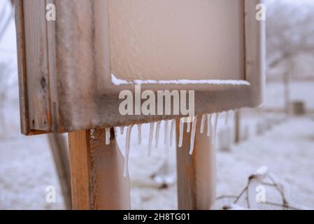 Ghiaccioli su un asse di legno in inverno Foto Stock