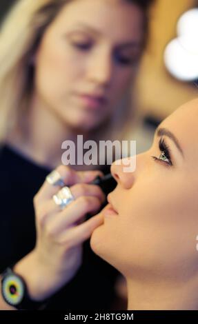 L'artista di trucco applica mascara. Bella donna faccia. Trucco perfetto Foto Stock