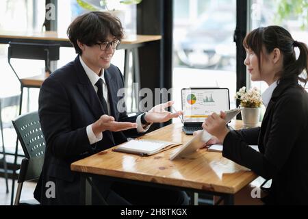 uomini d'affari che discutono i grafici e i grafici che mostrano i risultati del loro lavoro di squadra riuscito. Foto Stock