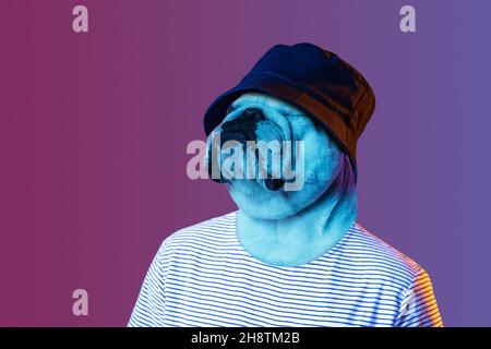 Opere d'arte contemporanea, collage concettuale. Giovane uomo elegante in cappello con testa di cane isolato su sfondo viola in neon. Surrealismo Foto Stock