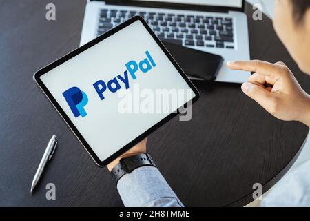 CHIANG mai, THAILANDIA - NOV 28, 2021 : l'uomo tiene l'ipad con le app PayPal sullo schermo. PayPal è un sistema di pagamento elettronico online. Foto Stock