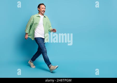 Vista a grandezza naturale del corpo di attraente uomo allegro che va copia spazio centro commerciale isolato su sfondo di colore blu chiaro Foto Stock