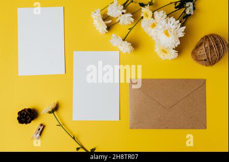la carta bianca con la busta e il fiore è posta su sfondo giallo Foto Stock