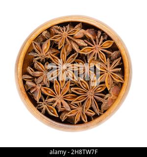 Frutti e semi di anice stellato, in una ciotola di legno. Conosciuto anche come staranise, anice stellato o badian. Pericarps secchi a forma di stella di Illicium verum. Foto Stock