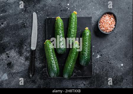 Cetrioli verdi maturi su una tavola di marmo. Sfondo nero. Vista dall'alto Foto Stock