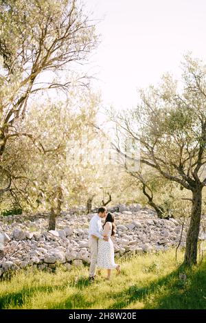 Uomo che bacia una donna incinta mentre si trova accanto alle pietre del parco Foto Stock