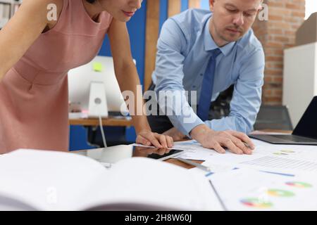 Uomo d'affari e donna che studiano documenti al tavolo in primo piano d'ufficio Foto Stock