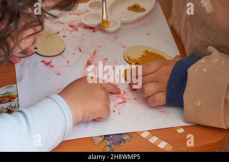 Le mani del bambino dipingono la figura di cuore di legno. Prescolare e famiglia Foto Stock