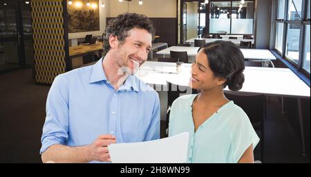 Immagine composita digitale di un uomo d'affari sorridente che tiene un documento guardando la giovane donna d'affari Foto Stock