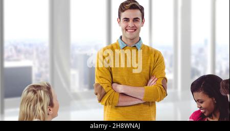 Ritratto di sorridente giovane uomo d'affari bello con le braccia incrociate in piedi tra le donne d'affari Foto Stock