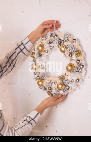 Donna appendere moderno rustico natale corona sul muro Foto Stock