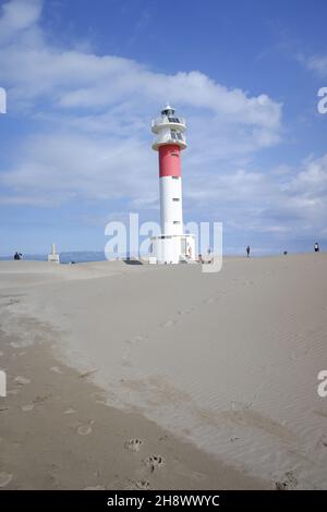 La gente cammina sulla sabbia dura vicino al faro della spiaggia di Fangar nel delta dell'Ebro. Foto Stock