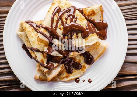 Piatto francese laici crepes con salsa di cioccolato nel piatto di ceramica su legno tavolo da cucina Foto Stock