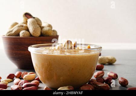 Vista ad angolo basso in una ciotola di vetro con burro di arachide su un tavolo di pietra. Concetto di alimentazione sana Foto Stock