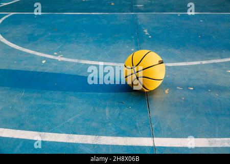 Pallina da basket gialla con cerchio e rete piazzata sul terreno sportivo nel parco in giornata di sole Foto Stock