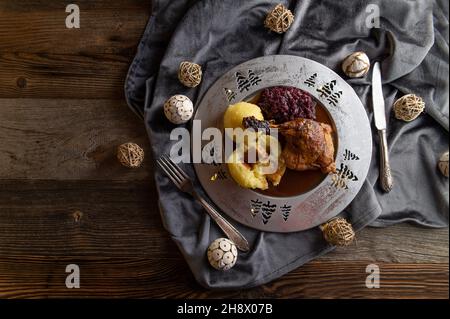 Tradizionale pasto tedesco di natale su un piatto con anatra arrosto gamba, cavolo rosso e gnocchi di patate. Servito con sugo di carne Foto Stock