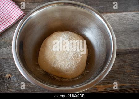 Impasto di lievito appena impastato in una ciotola su un tavolo rustico Foto Stock