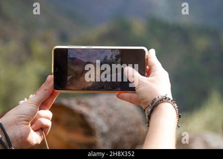 le mani femminili scattano le immagini con il telefono il paesaggio autunnale bello nelle montagne Foto Stock
