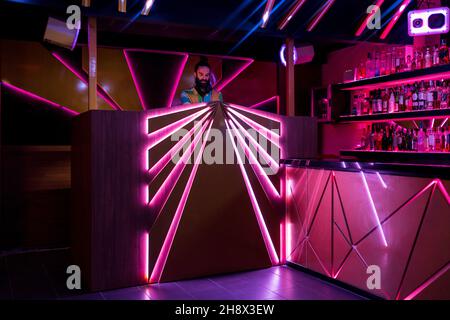 DJ maschile concentrato giovane bearded in piedi al banco illuminato nel moderno nightclub Foto Stock