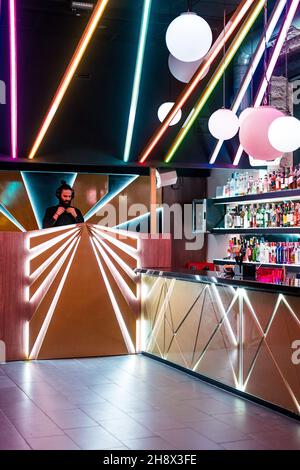 DJ maschile concentrato in cuffia in piedi al banco illuminato nel moderno nightclub Foto Stock