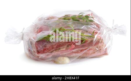 Carne fresca confezionata in una manica per la cottura. Pancia di maiale con verdure. Isolato su sfondo bianco. Foto Stock