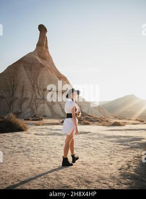 A corpo pieno giovane femmina turista in piedi su terreno sabbioso vicino cresta di montagna nel parco naturale di Bardenas Reales nella provincia di Navarra della Spagna Foto Stock