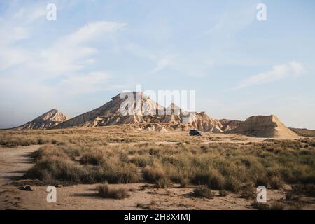 Vista pittoresca di un furgone in un terreno sabbioso nel parco naturale Bardenas Reales nella provincia di Navarra in Spagna Foto Stock