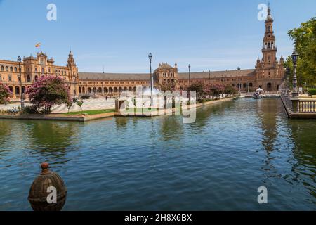 Siviglia, Andalusia, Spagna - 12 agosto 2021: Edificio rinascimentale centrale in piazza Plaza de Espana, vista sul fiume Guadalquivir con barche e gente Foto Stock