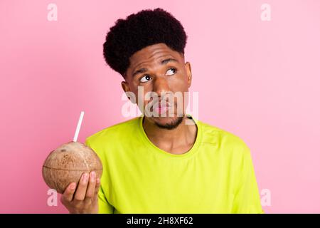 Ritratto di ragazzo dubbio attraente bere succo fresco meditando isolato su sfondo rosa pastello colore sfondo Foto Stock