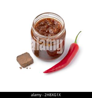Vaso di vetro con una variante di sambal, salsa al peperoncino, con pasta di gamberi isolata su sfondo bianco Foto Stock