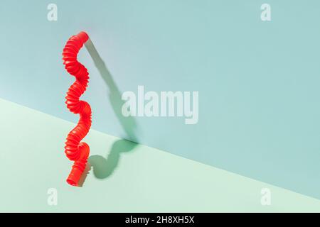 Il tubo pop curvo è appoggiato contro la parete. Vita morta moderna con giocattolo antistress. Foto Stock