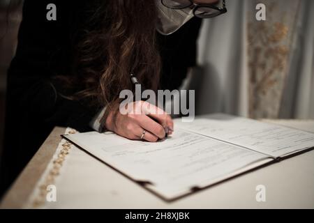 la donna firma un certificato di matrimonio su santa messa Foto Stock