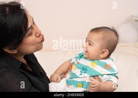 bambino di 3 mesi interagisce con la madre sorridendo mentre fa il suono con le labbra Foto Stock