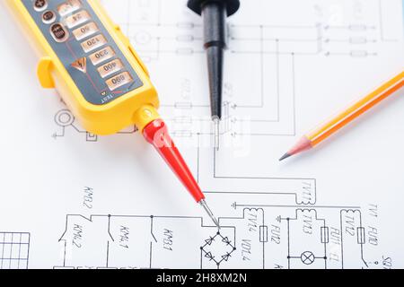 Indicatore di tensione giallo in primo piano sullo schema elettrico. Test e verifica delle reti elettriche Foto Stock