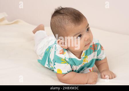 bambino di 3 mesi di età su stomaco a tutta la lunghezza tenendo la testa verso l'alto guardando lateralmente Foto Stock